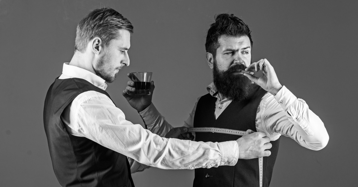 Zwei gutaussehende M�nner sind mit einem Ma�band zugange. Einer mi�t, der andere raucht gelangweilt Zigarre und h�lt einen Drink in der anderen Hand